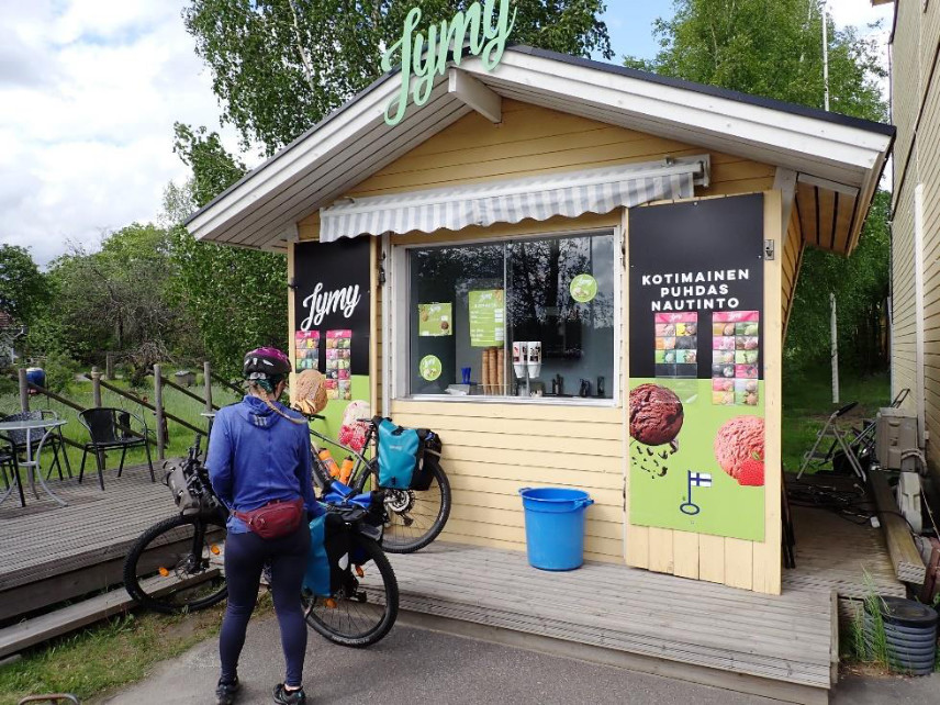 Henkilö pyörän kanssa kioskin edessä