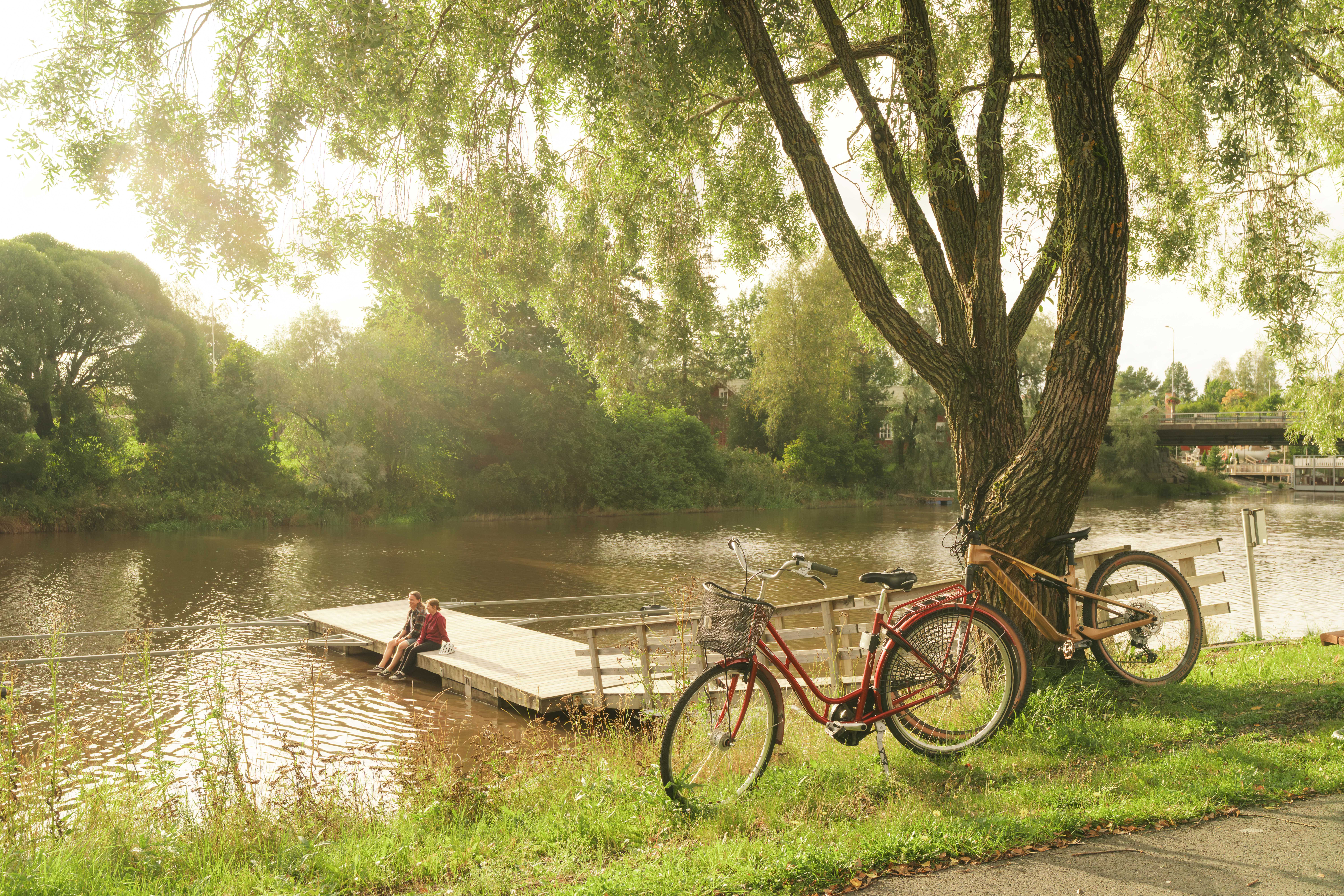 Pyöräilijä uittaa jalkojaan joessa laiturilla