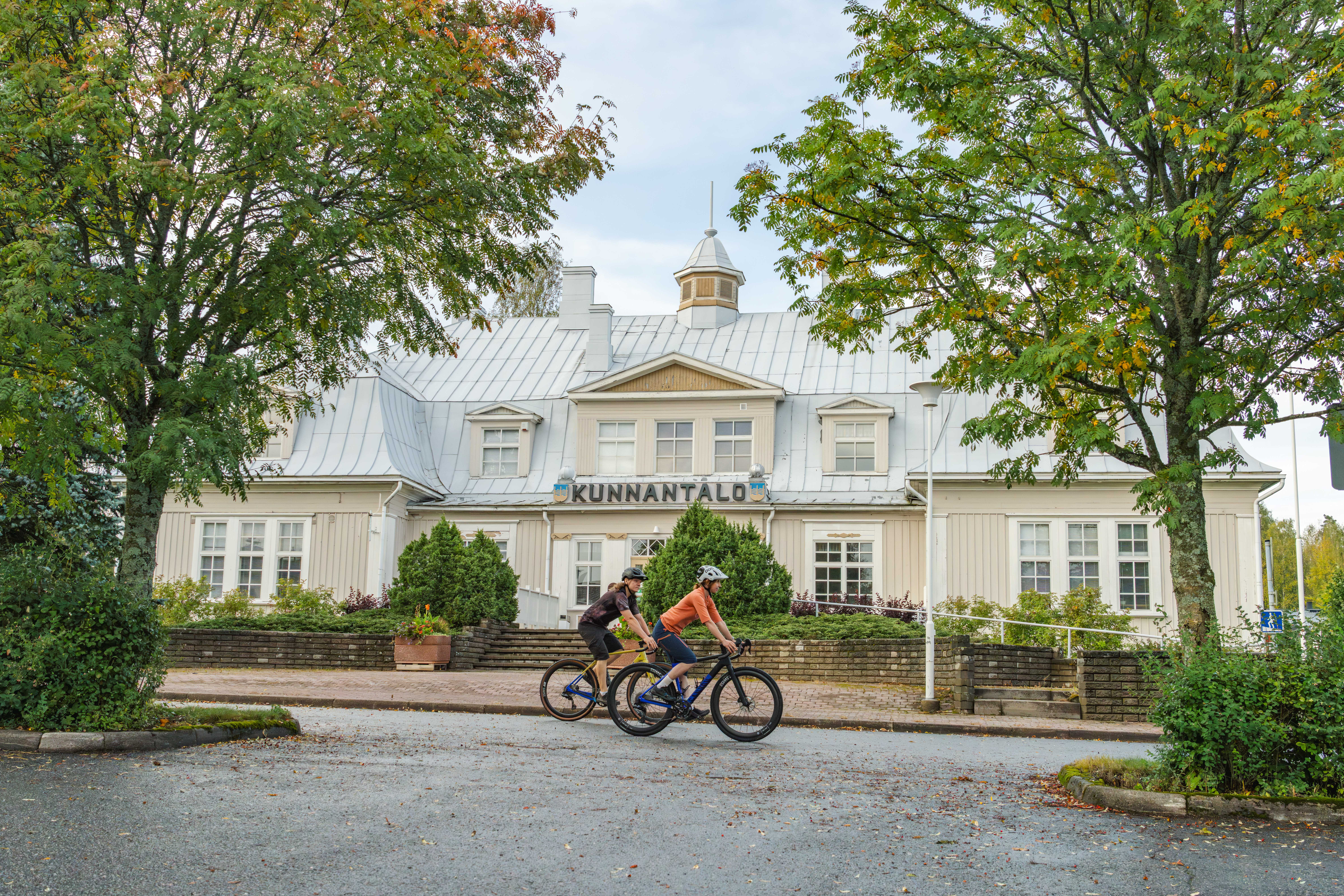 Kaksi pyöräilijää ohittaa Punkalaitumen kunnantalon